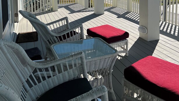 A covered outdoor deck with wicker furniture and a glass table, overlooking the ocean. - La Casa Bonita: 2  BR, 2  BA House in Crystal beach, Sleeps 8 (Bolivar Peninsula)