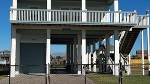 A two-story building with a balcony, a garage, and a staircase. - La Casa Bonita: 2  BR, 2  BA House in Crystal beach, Sleeps 8 (Bolivar Peninsula)