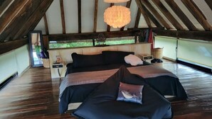 A bedroom with a wooden ceiling and a large bed with dark bedding. - This home features lush garden & private pool. (Isla mujeres)