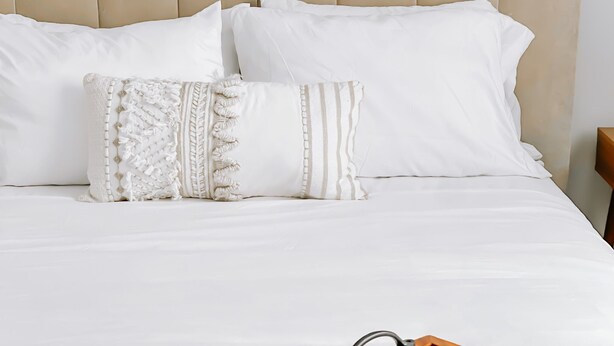 A neatly made bed with white bedding and two decorative pillows.