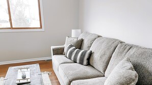 A living room with a grey sofa, a black coffee table, and a patterned throw pillow.