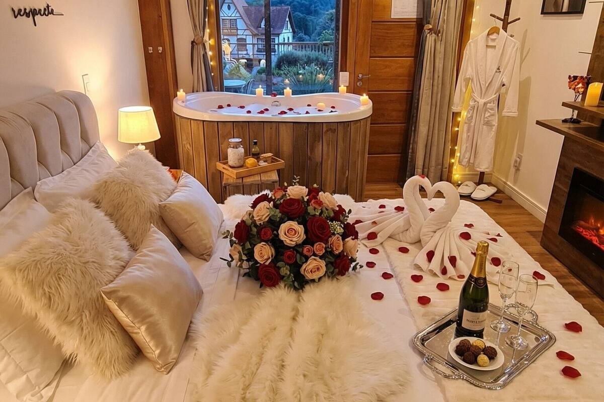 Een luxe slaapkamer met een groot bed, uitzicht op een berg, een klein rond tafeltje met kaarsen en een open haard.
