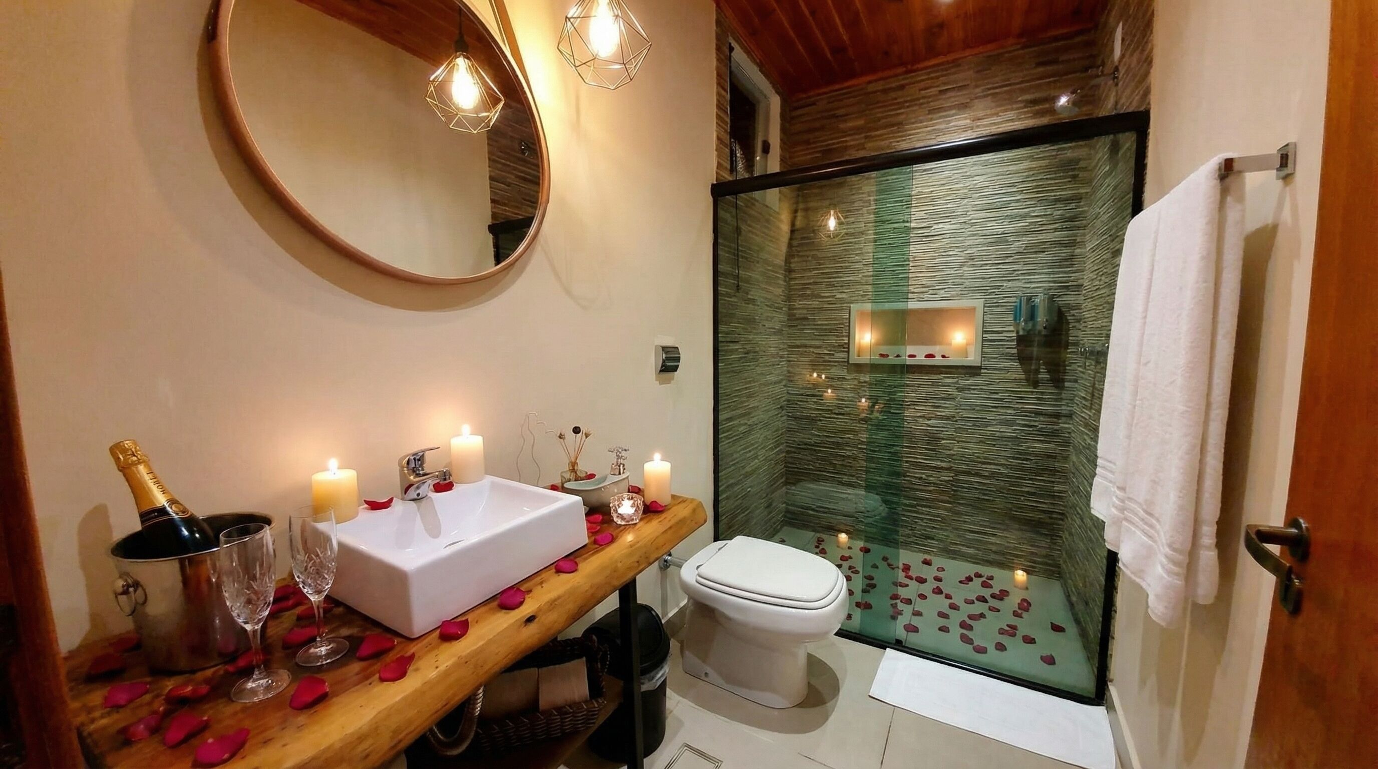 A bathroom with a wooden vanity, a round mirror, a white sink, and a glass shower enclosure.