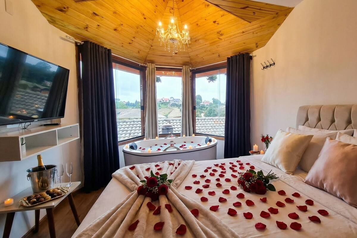Een hotelkamer met een groot bed, een televisie, een badkuip en uitzicht op de stad.