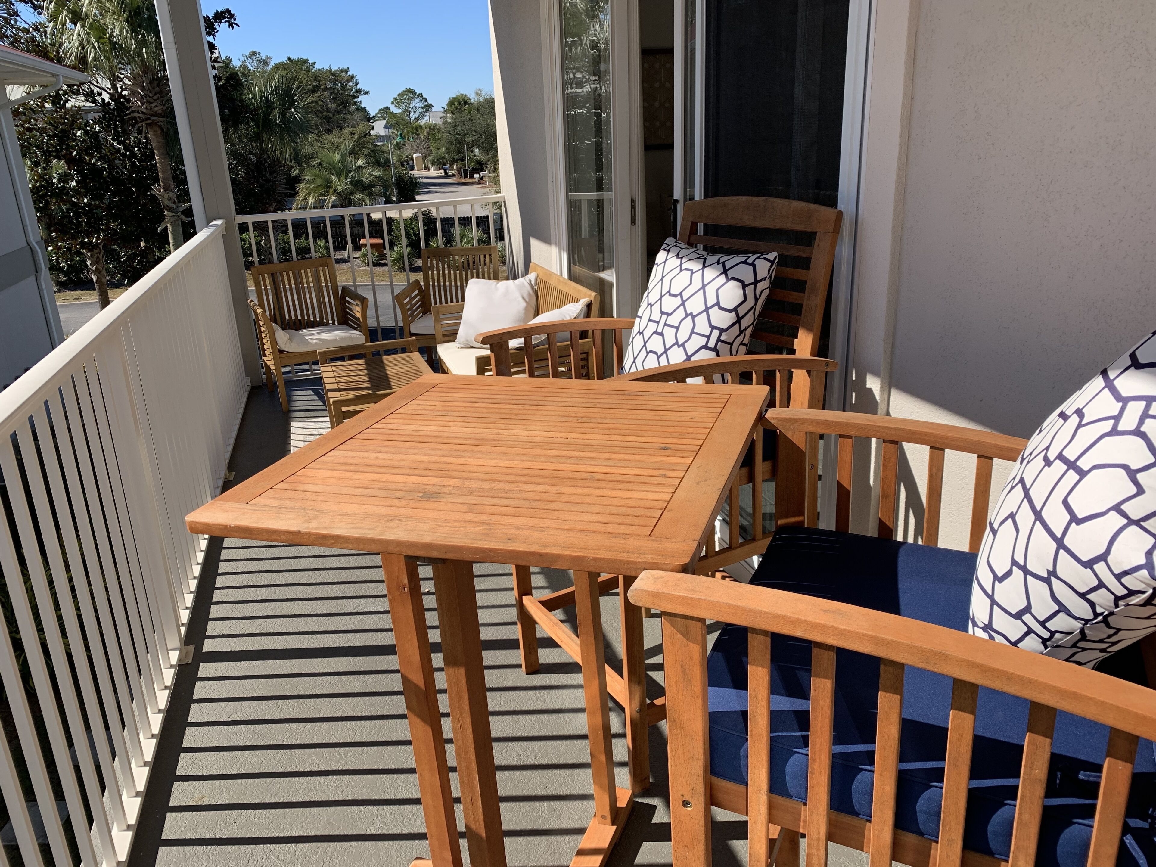Eine Holzterrasse mit Tisch und Stühlen, einem weißen Geländer und Blick auf die Umgebung.