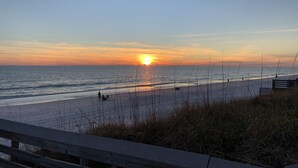 A beach with a sunset, calm sea, and a wooden walkway. - Welcome to Rollin Tide Villas in the heart of beautiful 30A. (Santa Rosa Beach)
