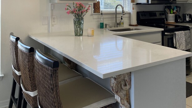A modern kitchen with a central island, white cabinetry, and a hanging light fixture. - Welcome to Rollin Tide Villas in the heart of beautiful 30A. (Santa Rosa Beach)