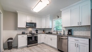 A modern kitchen with white cabinetry, a stainless steel oven, a microwave, and a dishwasher. - Marietta! Near the Square, Pets & Long stays ok. Entire home (Marietta)