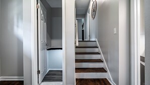A hallway with a wooden staircase and a door leading to another room. - Marietta! Near the Square, Pets & Long stays ok. Entire home (Marietta)