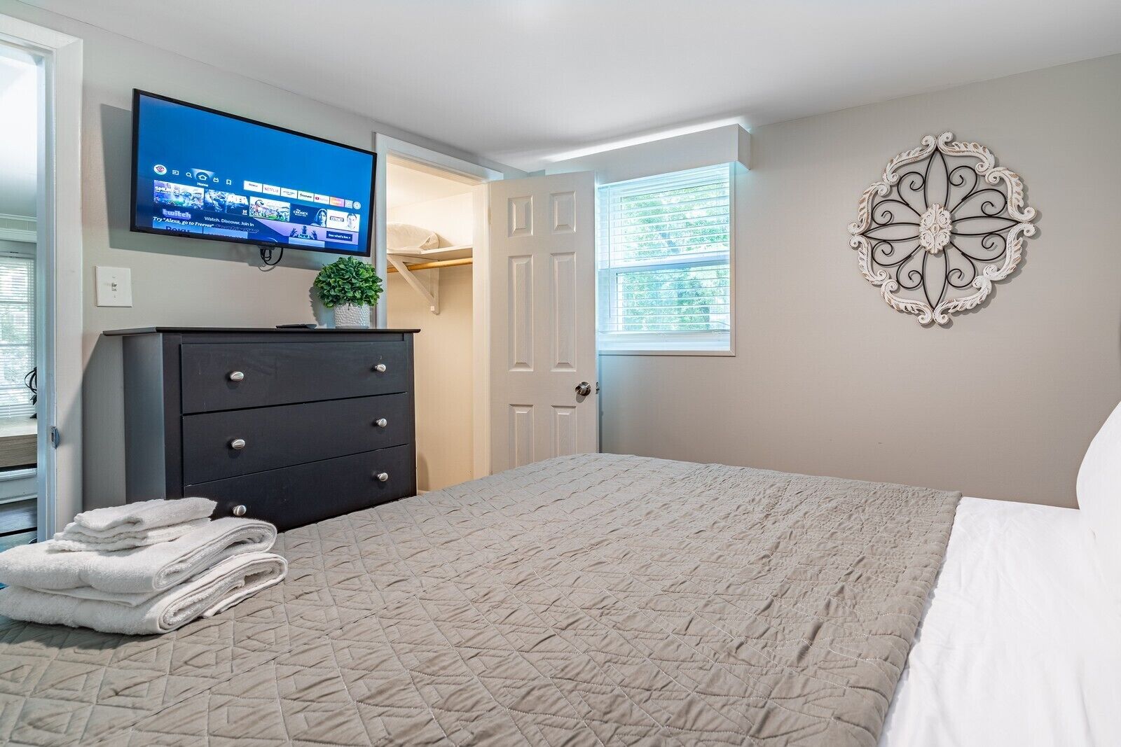 Une chambre à coucher avec un lit, une commode, un téléviseur fixé au mur et un élément décoratif mural.