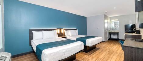 Quarto de hotel com duas camas, uma escrivaninha, um espelho e uma televisão.