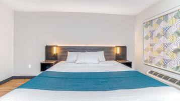 A modern hotel room with a large bed, two bedside tables, and a decorative wall panel.