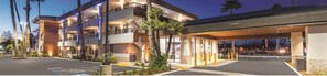 A multi-story hotel with a covered entrance, a parking lot, and palm trees. - Studio 6 Suites – Stockton, CA – Waterfront (Stockton)