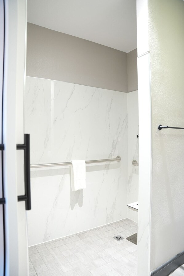 A modern bathroom with a marble wall, a towel rack, and a shower area.