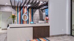 A modern reception desk with a large '6' sign, a computer, and a phone. - Studio 6 Suites – Stockton, CA – Waterfront (Stockton)
