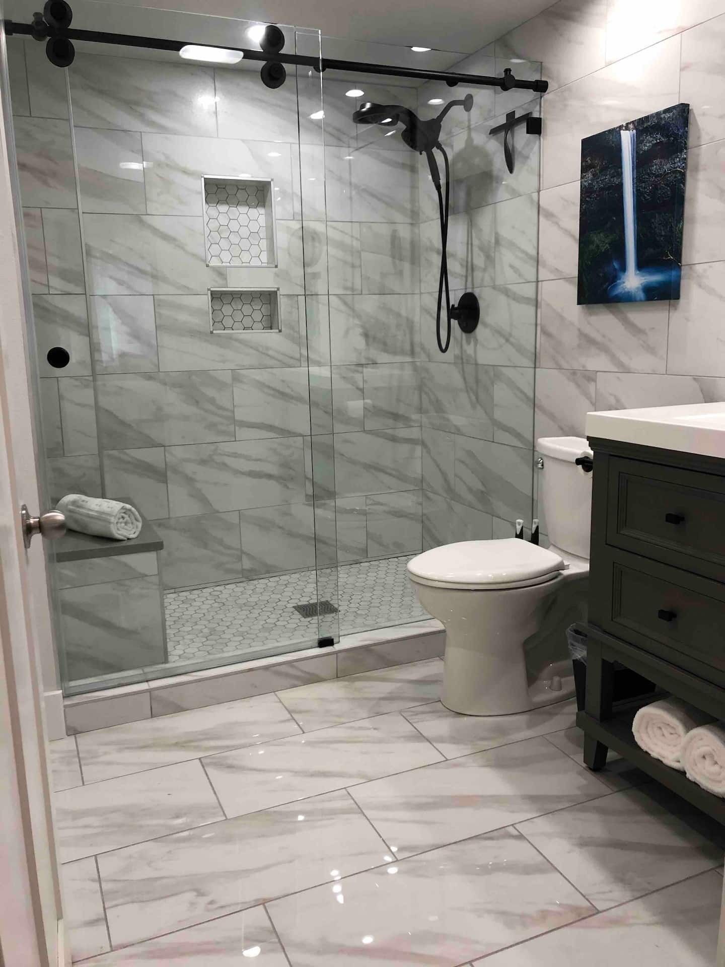 Une salle de bain moderne avec une douche à parois de verre, des toilettes et un meuble-lavabo avec un miroir.