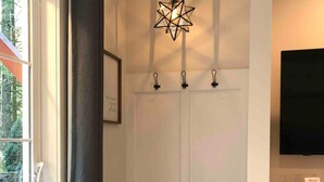 Une pièce avec un banc, un luminaire au plafond et un téléviseur fixé au mur.