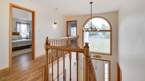 A staircase with wooden railings leading to a bedroom with a bed and a window. - Private Heated Pool/Hot Tub/Huge Game Room/Sauna/Fire Pit/Huge Yard/3300 sq ft! (Stroudsburg)