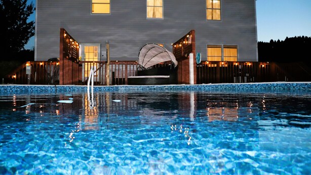 A swimming pool with a house in the background. - Private Heated Pool/Hot Tub/Huge Game Room/Sauna/Fire Pit/Huge Yard/3300 sq ft! (Stroudsburg)