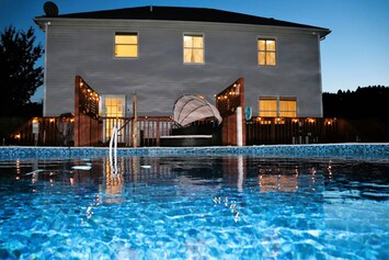Nighttime view of the pool and back of the home