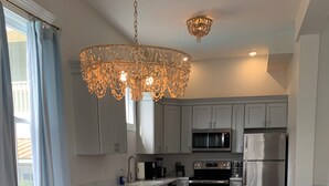 A modern kitchen with grey cabinets, stainless steel appliances, and a chandelier. - By Forsyth Park, W/ King Bed +New Bath & Kitchen! (Savannah)