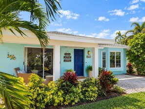 A two-story building with a blue door, a welcome sign, and a number sign. - 706 Aqua Vista · NEW Heated Southern Exposure Pool (Naples)