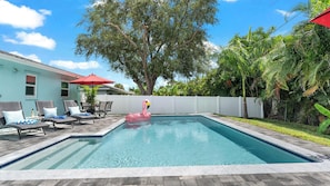 A swimming pool with lounge chairs and a flamingo float.