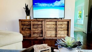 Un salon avec un téléviseur, un meuble en bois et un magazine sur une table basse.