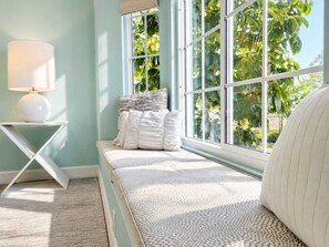 A room with a window seat, a lamp, and a view of greenery outside. - 706 Aqua Vista · NEW Heated Southern Exposure Pool (Naples)