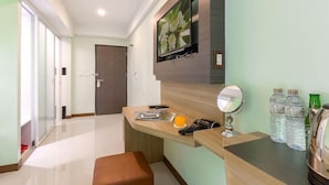 Habitación de hotel con escritorio de madera, espejo, teléfono, vaso de jugo de naranja y agua embotellada.