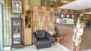 Una zona de recepción con un sillón de cuero negro, un aparador de madera con puertas de cristal y una estatua de una divinidad.