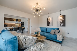 A modern living room with a blue sofa, patterned armchairs, a coffee table, and a chandelier. - Holiday House Paula - Three-Bedroom Holiday Home with Private Pool (Privlaka)