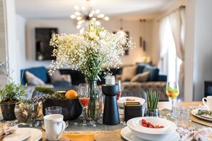 A dining table set with various dishes, a vase of flowers, and a modern chandelier in the background. - Holiday House Paula - Three-Bedroom Holiday Home with Private Pool (Privlaka)