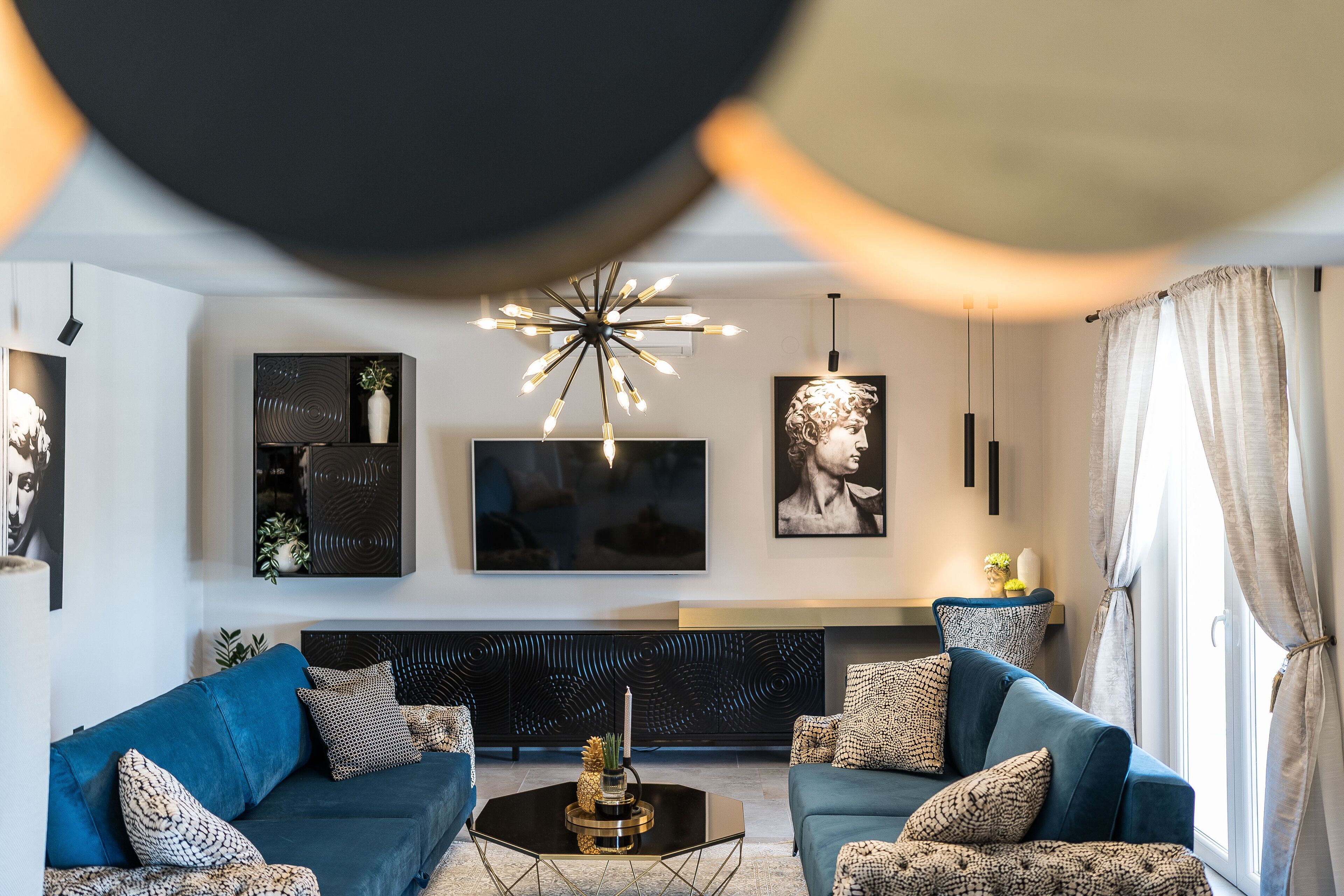 Een moderne woonkamer met twee banken, een salontafel, een televisie en decoratieve objecten.