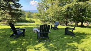Un espace extérieur aménagé avec des chaises Adirondack et un foyer en pierre.