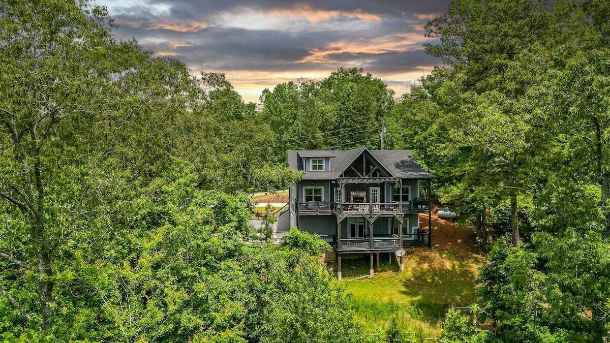 A two-story house surrounded by dense forest.