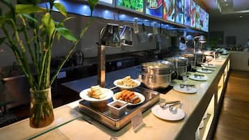 A buffet setup with various food items and cooking equipment.