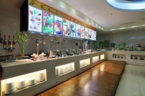 A buffet area with a long counter, multiple food display screens, and a variety of dishes. - Rightway Xiyue Hotel (Chengdu)