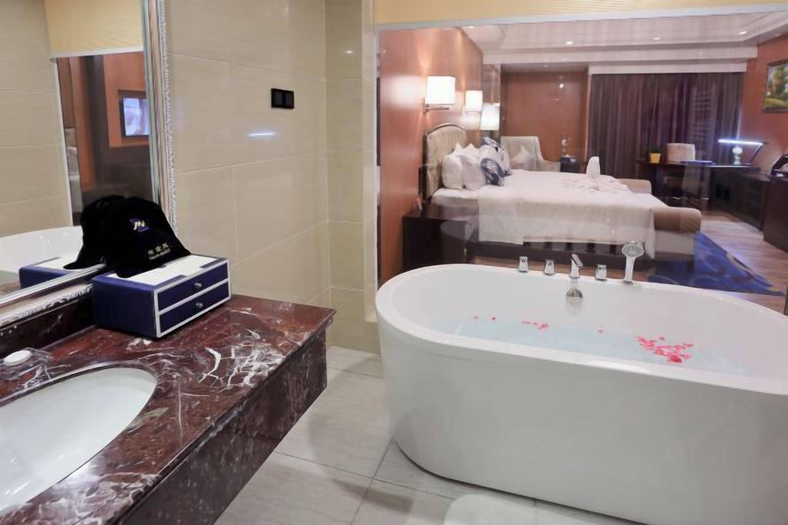 A bathroom with a marble sink, a bathtub, and a large mirror.