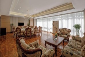 A spacious living room with a dining area, large windows, and a chandelier. - Rightway Xiyue Hotel (Chengdu)