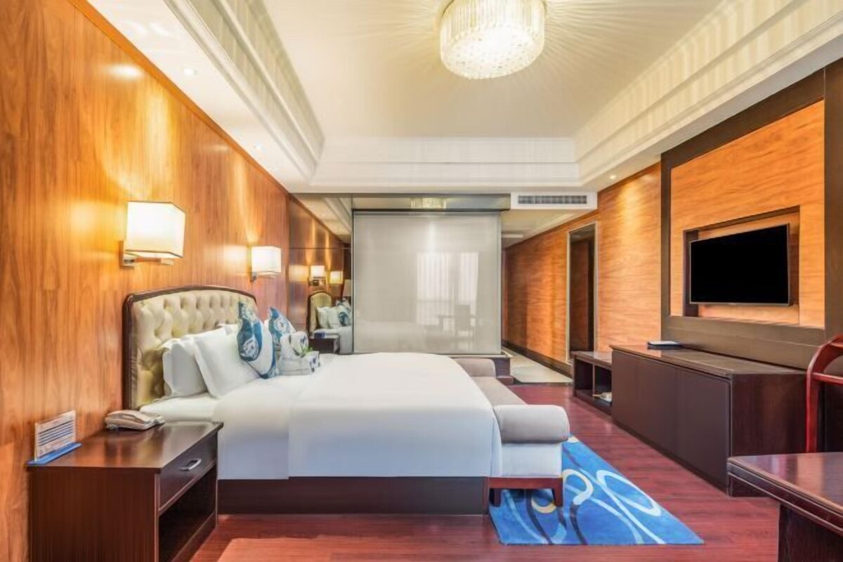A hotel room with a large bed, a TV, and a desk.