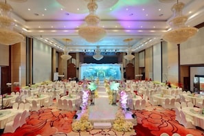 A banquet hall with round tables, a stage, and a red carpet. - Rightway Xiyue Hotel (Chengdu)