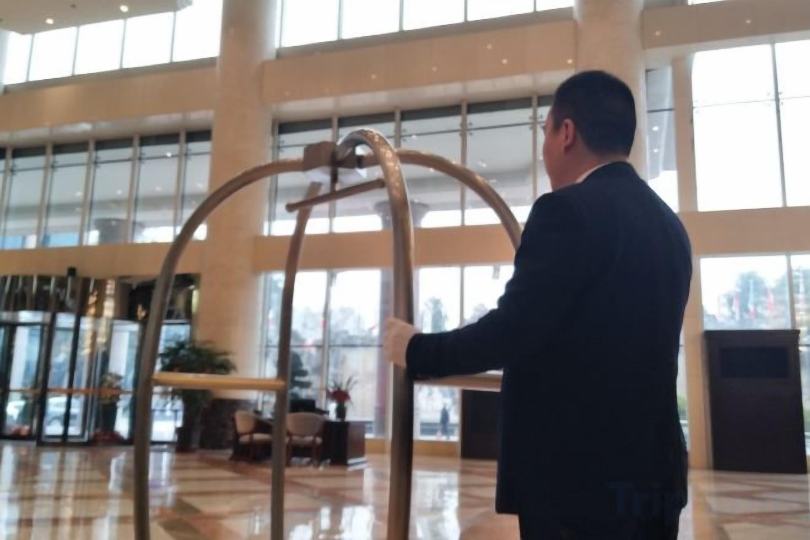 A man in a suit interacting with a large, circular metal structure in a spacious lobby with large windows and a polished floor.
