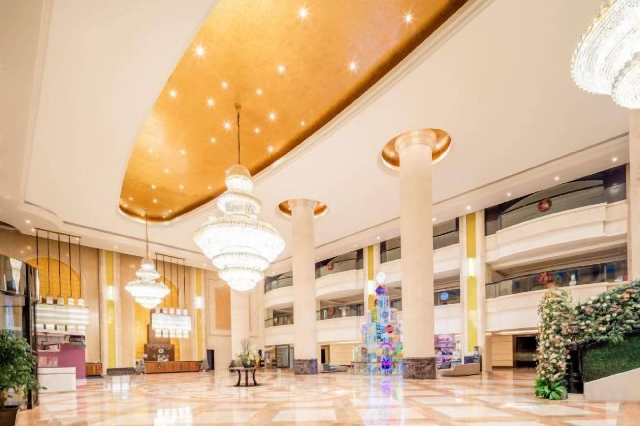 Eine großzügige Lobby mit hohen Decken, Kronleuchtern und einer zentralen Zierensäule.