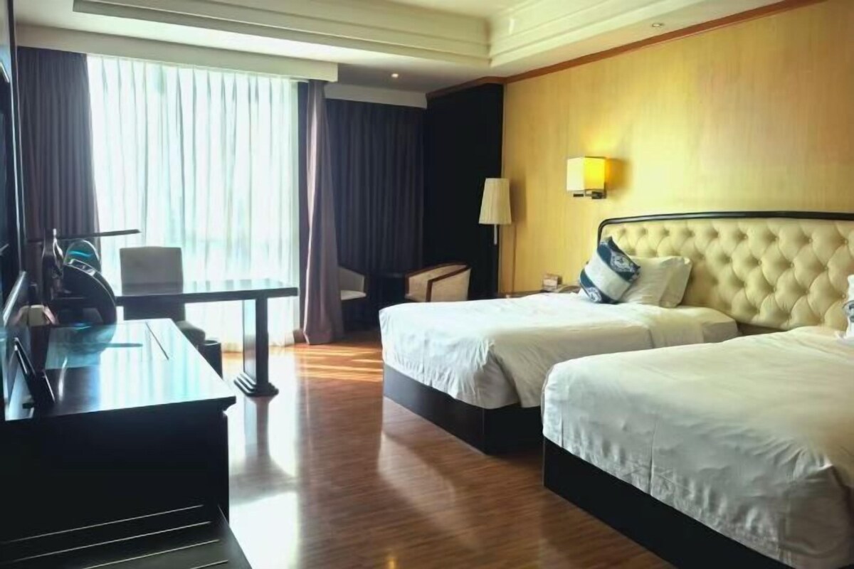 A hotel room with two beds, a desk, and a chair.