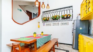 A dining area with a wooden table, benches, and a checkered tablecloth. There are potted plants on the table and a wall-mounted flower arrangement above. - Ayenda Casa La Castellana (San Juan de Pasto)