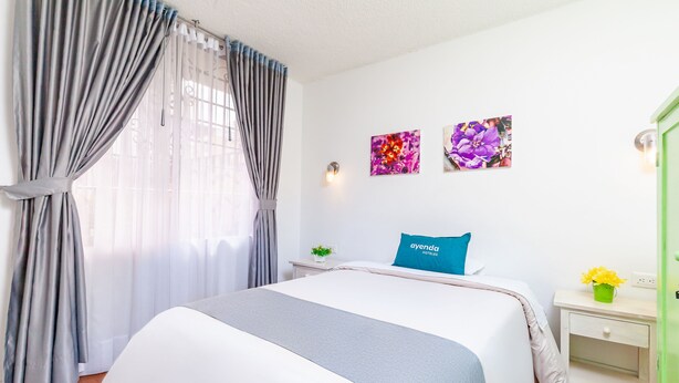 A hotel room with a bed, a nightstand, a lamp, and two wall-mounted flower paintings. - Ayenda Casa La Castellana (San Juan de Pasto)