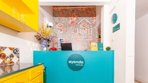 A reception area with a teal counter, a floral wall, and a clock on the wall. - Ayenda Casa La Castellana (San Juan de Pasto)
