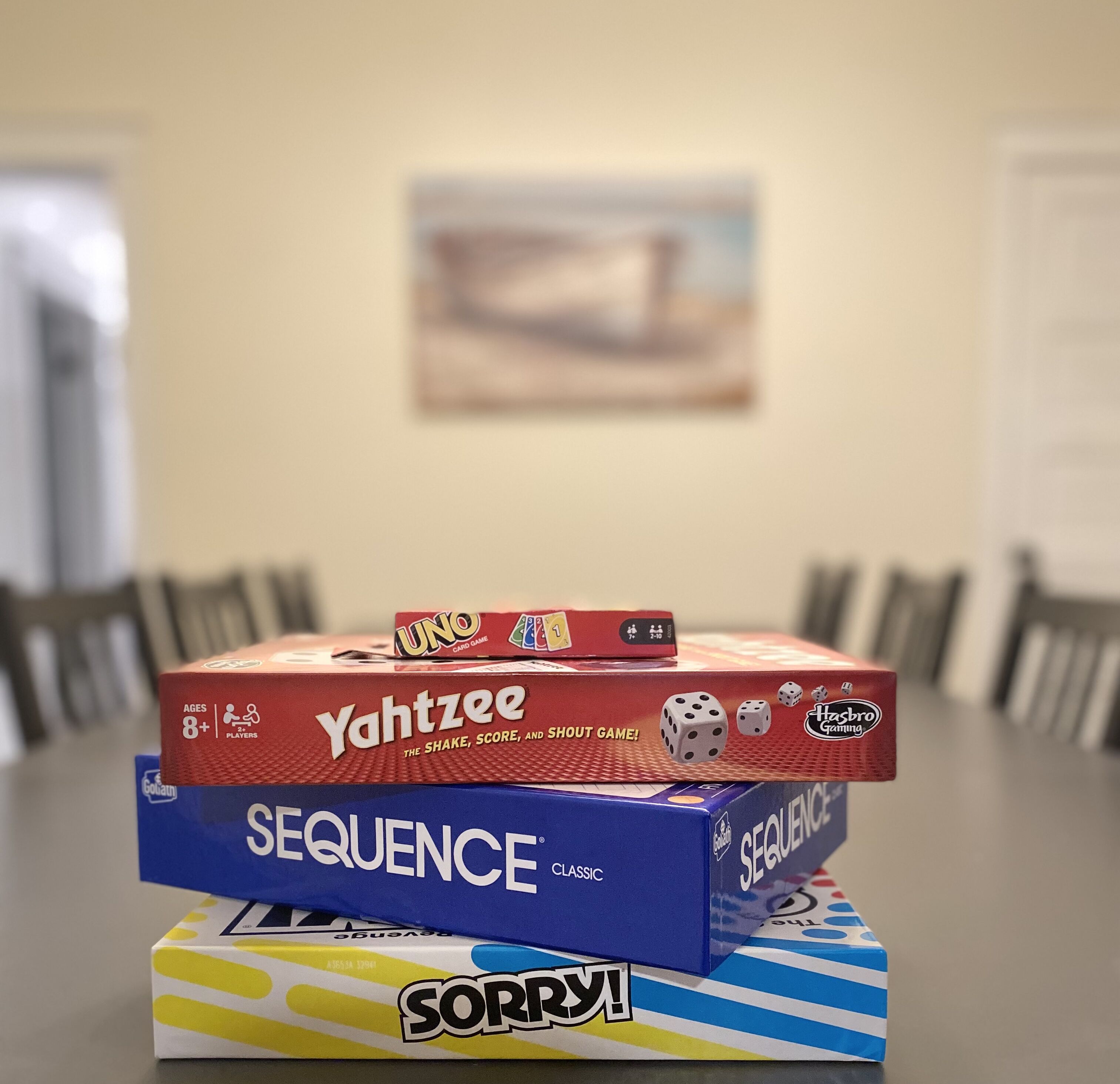 Une pile de jeux de société est posée sur une table, avec un arrière-plan flou.