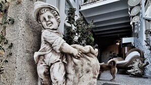 Una estatua de piedra de un niño en un saliente, un perro y una escalera que conduce a un nivel superior.